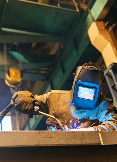 Young man with protective mask welding in a factory